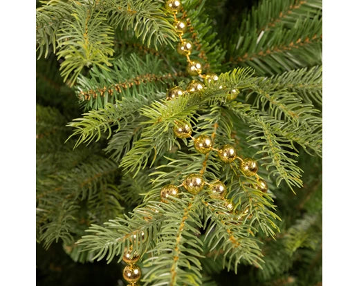 Shiny light gold polystyrene bead garland draped over green pine tree branches.