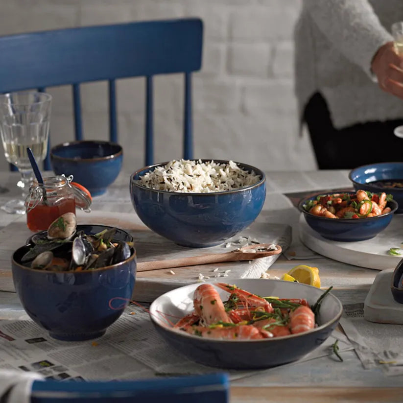 Denby Imperial Blue serving bowl filled with rice on a table set with seafood dishes and drinks.