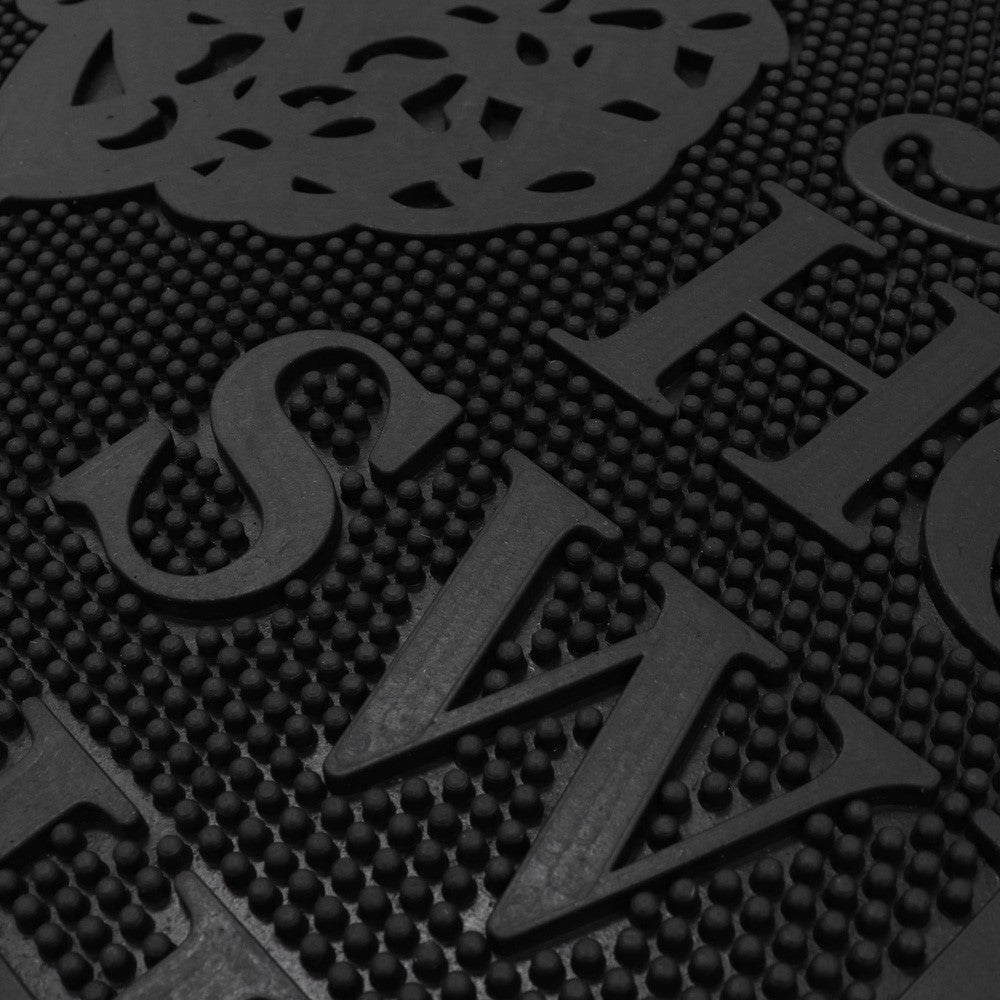 Close-up of black rubber Home Sweet Home scraper mat with raised textured surface and lettering.