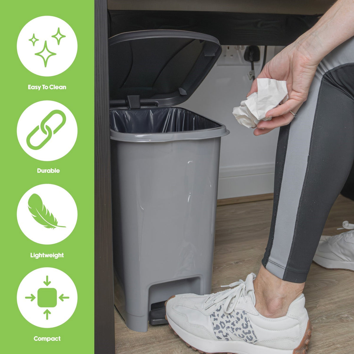 Grey JVL Slim Pedal Bin 10L with open lid, foot pressing pedal, and hand holding crumpled paper above it