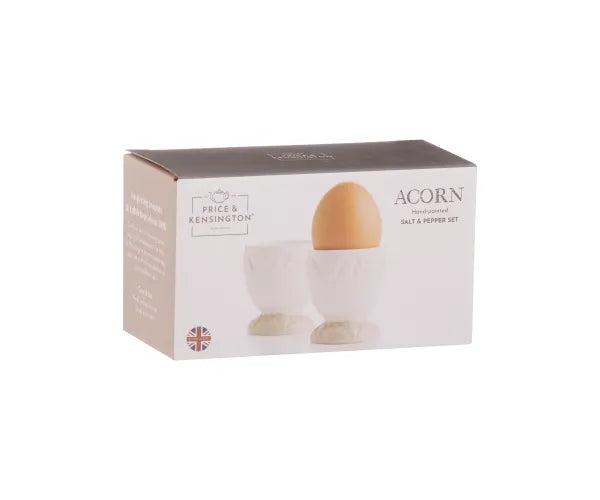 Boxed set of two white ceramic acorn-shaped egg cups with one holding a brown egg.