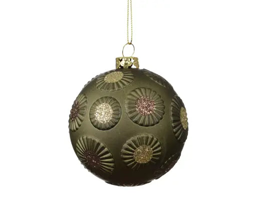 An olive green glass Christmas ornament with embossed sunburst patterns and glittery gold, pink, and green floral centers, hanging from a gold string against a white background.