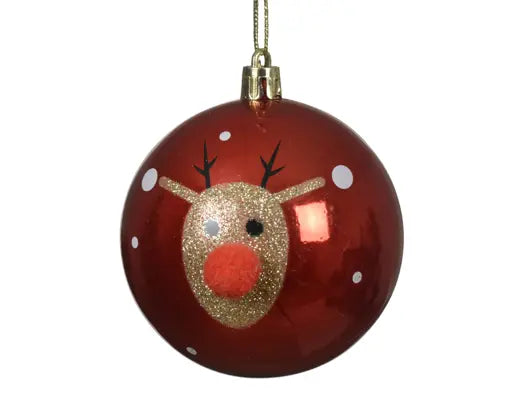 A round red Christmas ornament featuring a glittery gold reindeer face with a red nose, black antlers, and white snowflake details, hanging by a gold string against a white background.