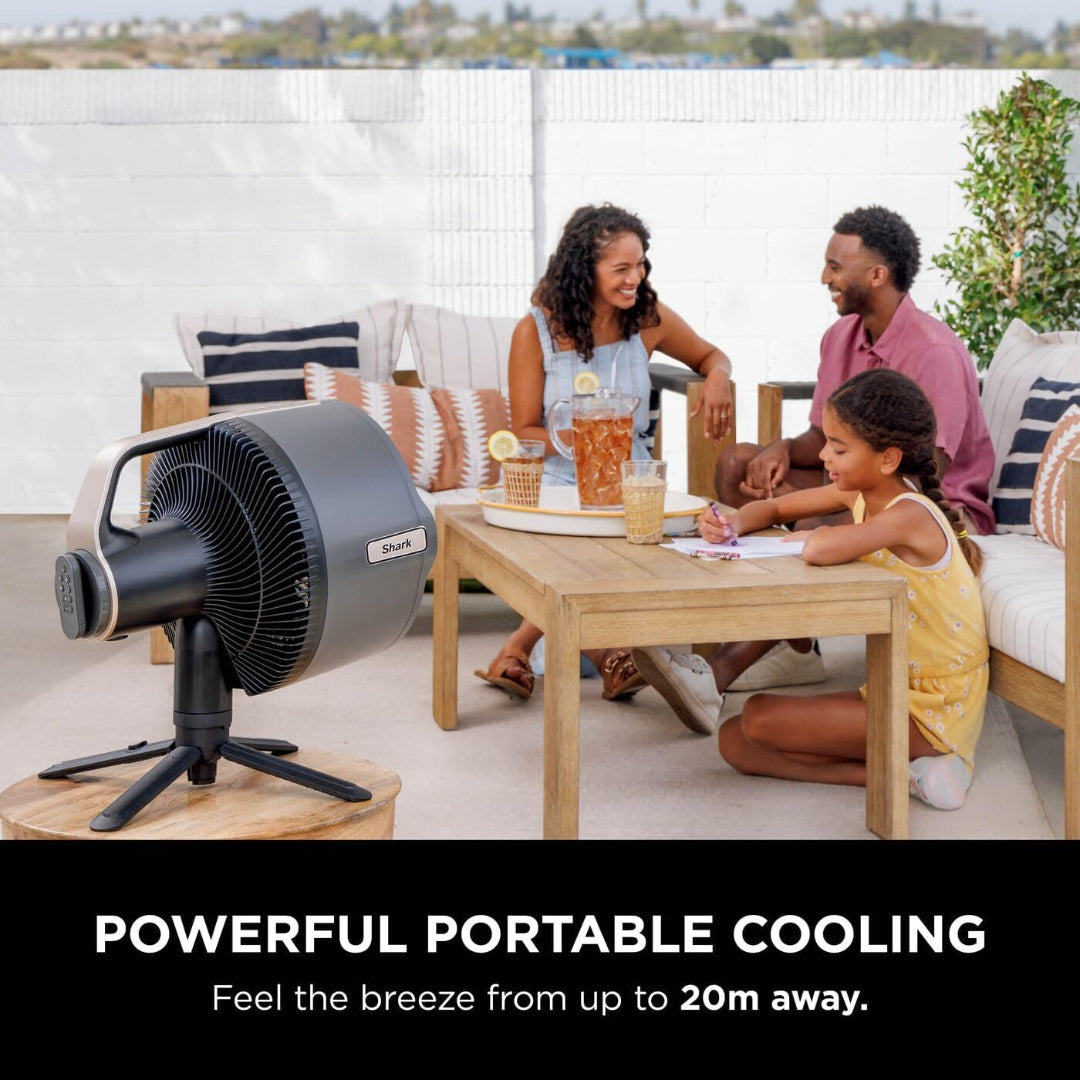 Shark FlexBreeze Pro Mist fan on a wooden table with a family sitting and enjoying outdoors behind it
