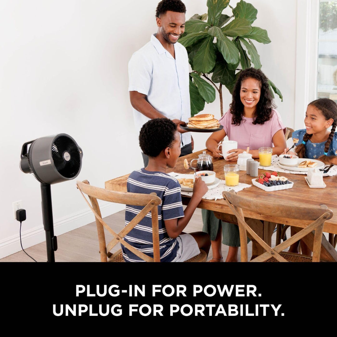 Shark FlexBreeze Pro Mist fan plugged in beside a family enjoying breakfast at a wooden table indoors.
