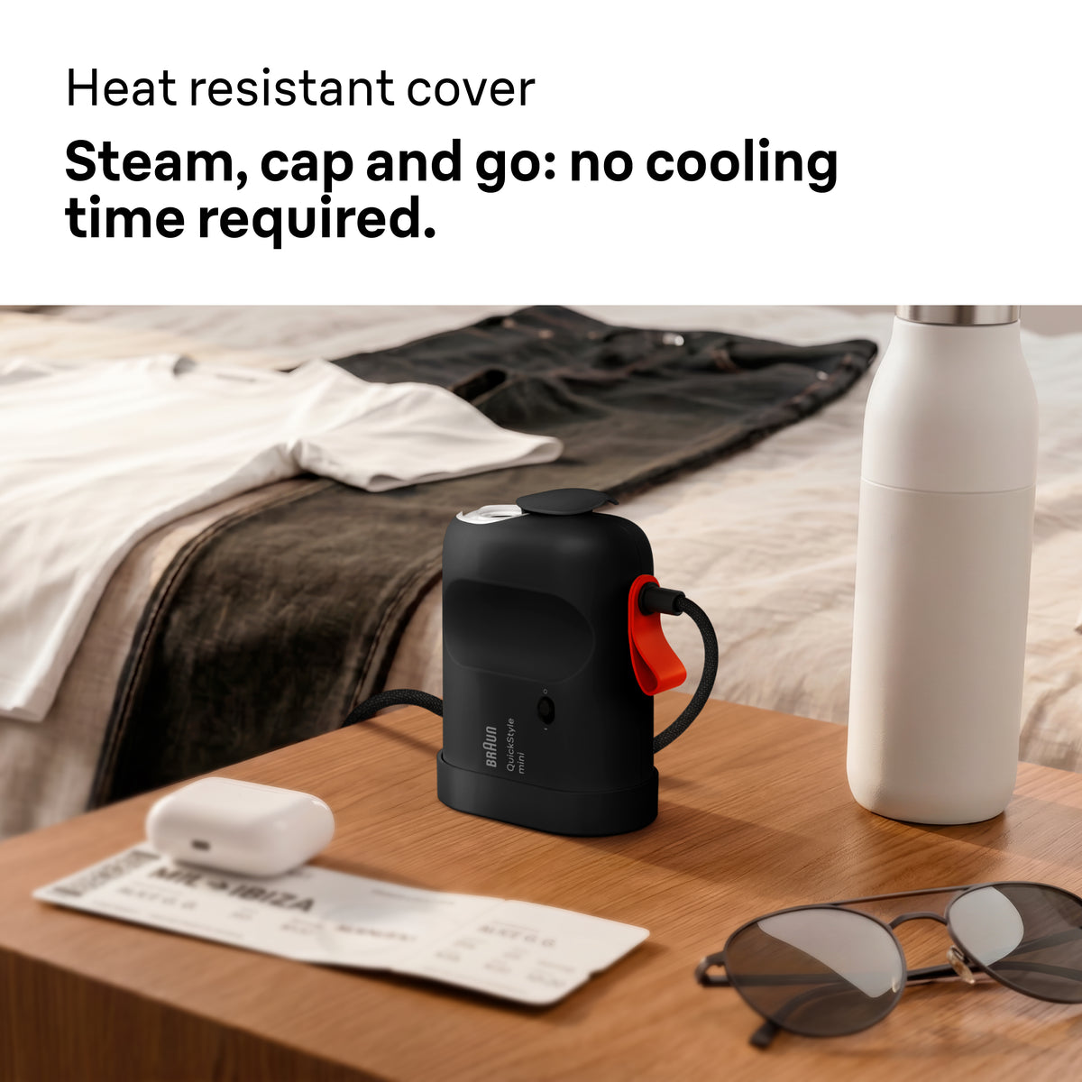Braun Carestyle Mini Travel Garment Steamer on a wooden table with sunglasses, ticket, and white bottle nearby