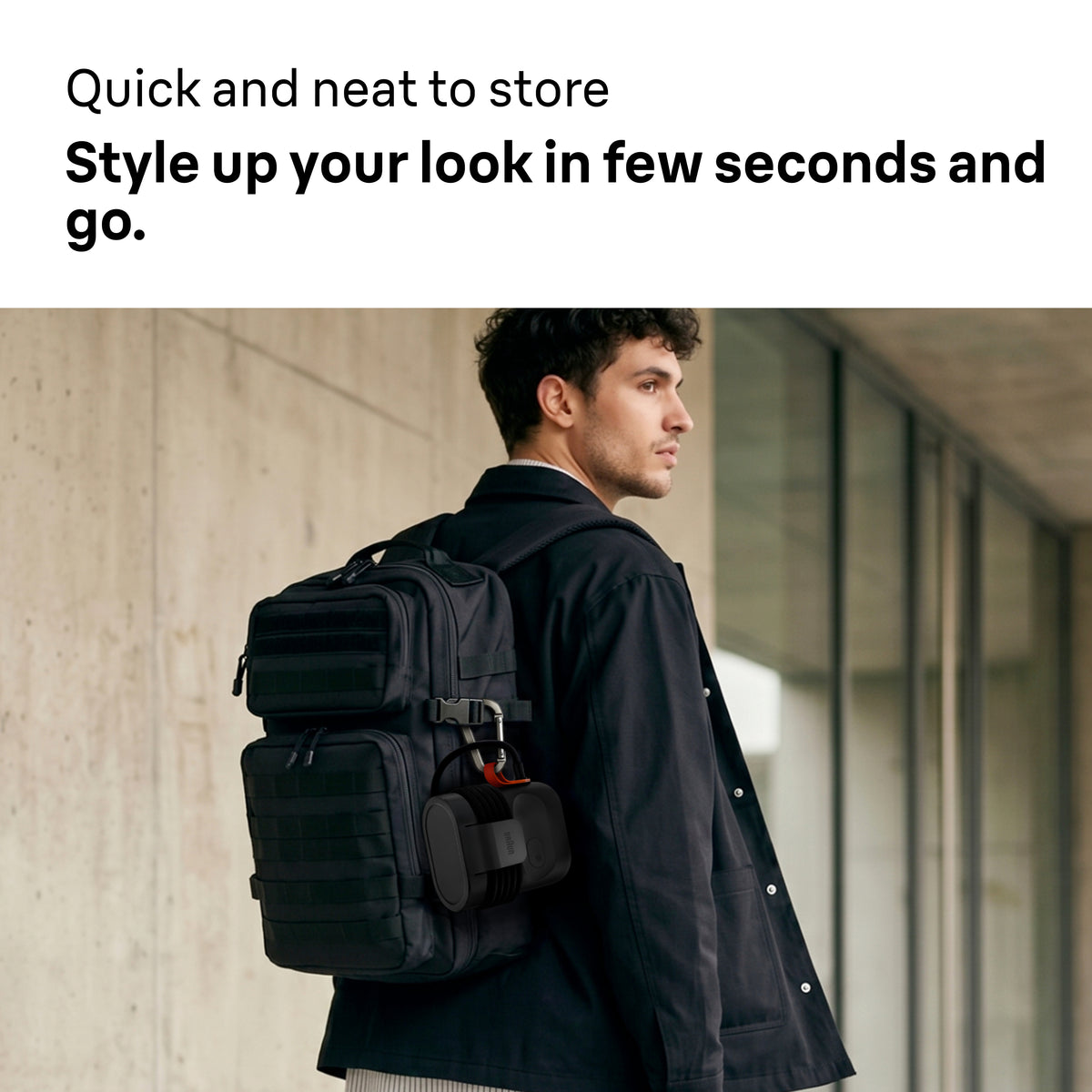 Braun Carestyle Mini Travel Garment Steamer clipped to a black backpack worn by a man in a black jacket.