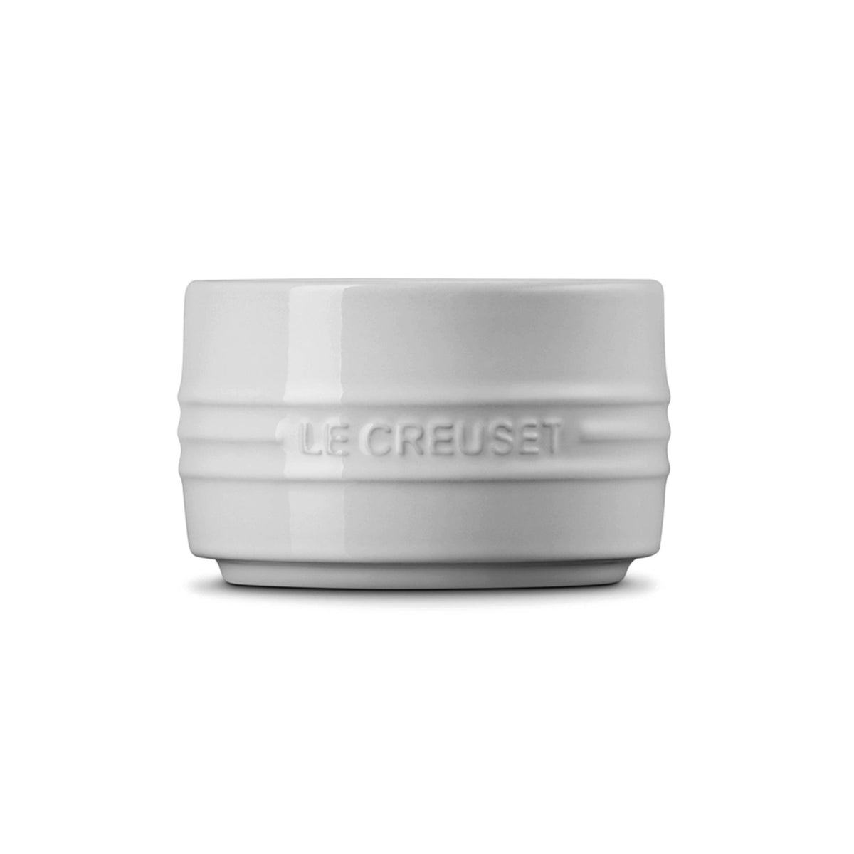White Le Creuset stackable ramekin dish with embossed logo on the side, front view.