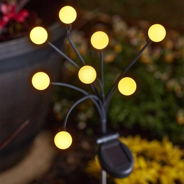 Mini Ball Stake Light with eight warm white glowing orbs on black stems, solar panel visible near base.