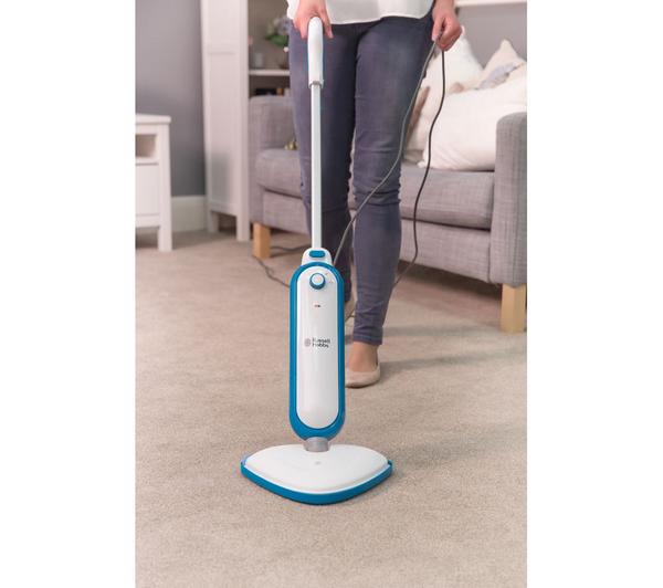Person using Russell Hobbs Steam and Clean Steam Mop RHSM1001G on a carpeted floor in a living room.