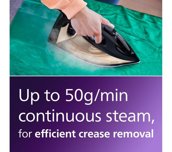 Hand holding Philips Steamglide Elite black and gold steam iron pressing a green fabric with steam visible