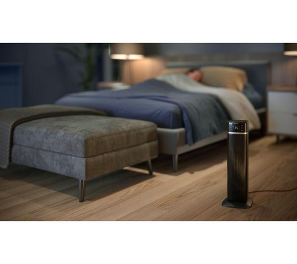 Philips Smart Tower Heater 5000 Series in dark grey standing on wooden floor near bed in dimly lit bedroom
