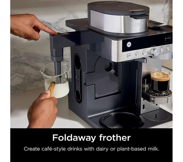 Ninja Prestige DualBrew System with foldaway frother steaming milk in a glass beaker on a kitchen counter.
