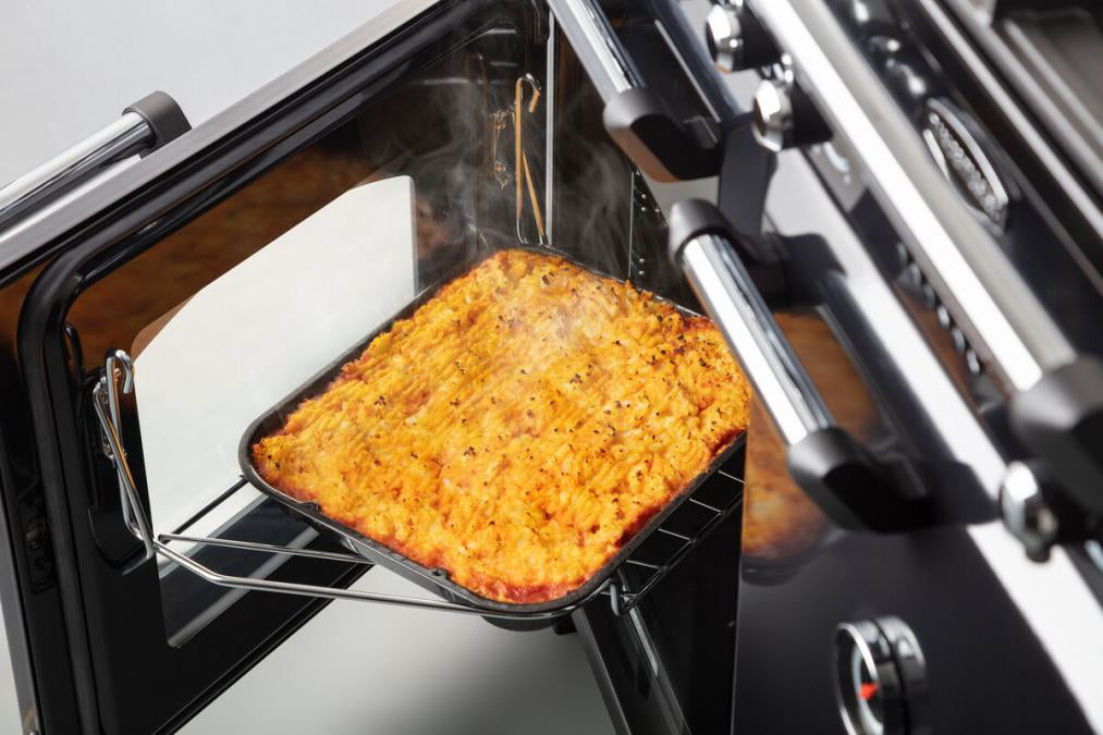 Rangemaster Classic Deluxe oven door open with steaming baked dish inside on a pull-out shelf