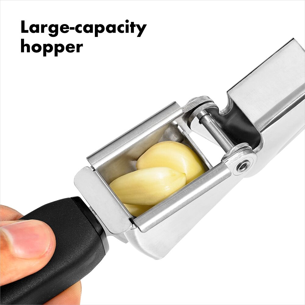 Oxo Garlic Press with black handle holding three garlic cloves in the stainless steel hopper.