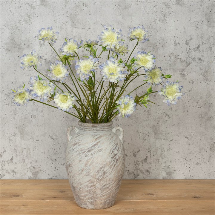Scabiosa Spray 84cm with pale yellow and blue flowers arranged in a textured ceramic vase on a wooden surface