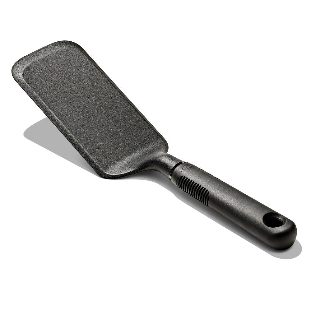 Oxo Nylon Lasagne Turner with a wide, flat, slightly angled black head and ergonomic handle with hanging hole.