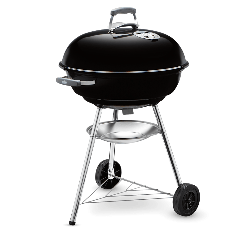 Weber Compact Kettle charcoal barbecue with black lid, silver legs, two wheels, and ash catcher tray below grill bowl