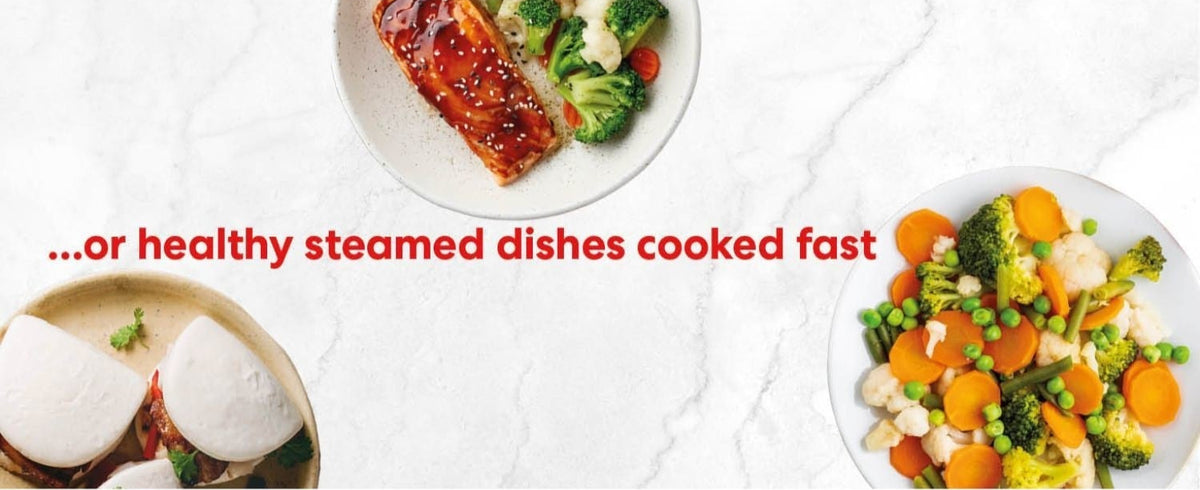 Three plates with steamed dishes including salmon, vegetables, and bao buns on a white marble surface.