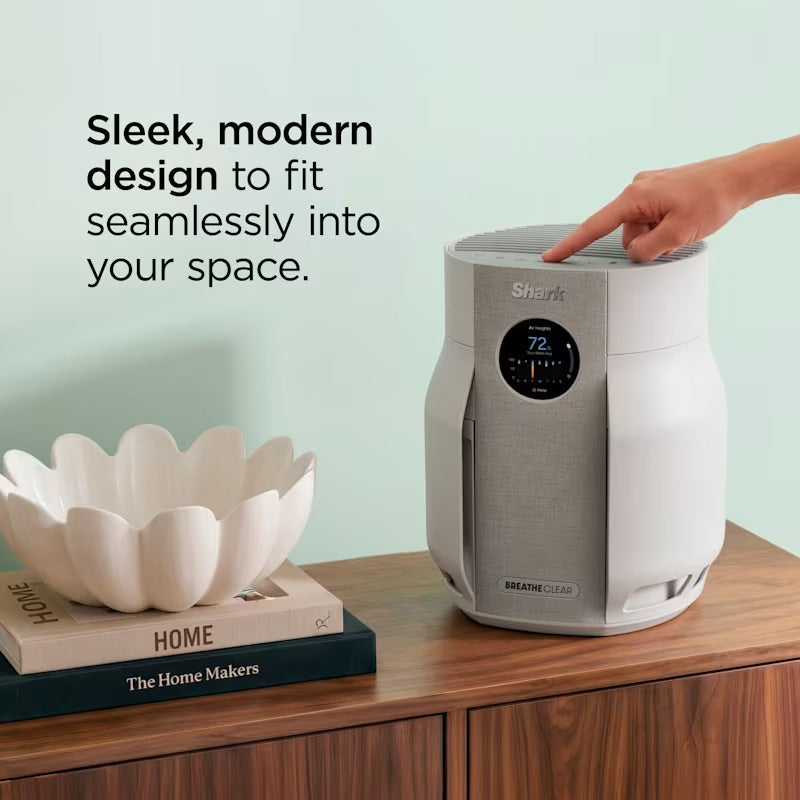 Shark BreatheClear Compact Air Purifier Dove on wooden surface with hand touching top controls and decorative bowl nearby.