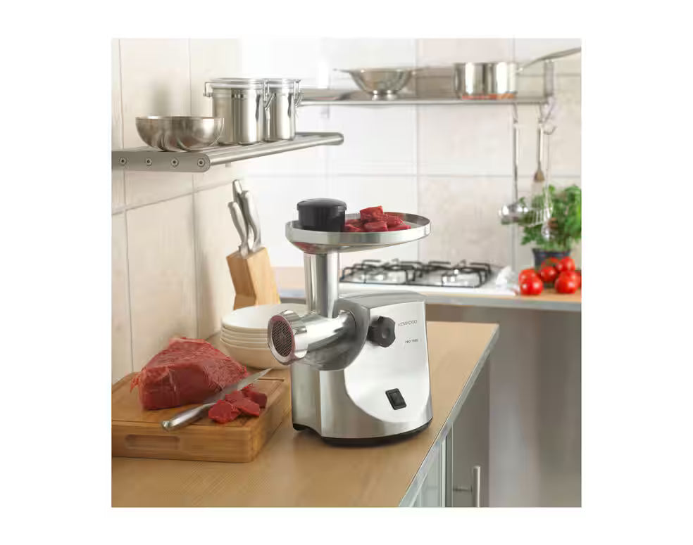 Kenwood Food Mincer MG510 on kitchen counter with raw beef pieces on tray and cutting board nearby