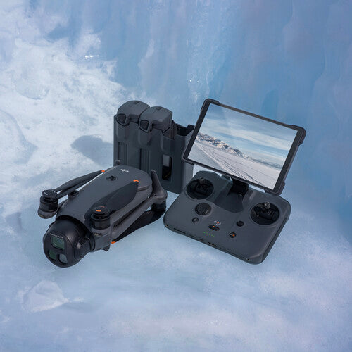 DJI Mavic 4 Pro drone folded next to remote controller with screen and battery charging hub on icy surface