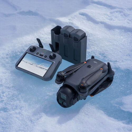 DJI Mavic 4 Pro drone with folded arms, remote controller showing snowy landscape, and three batteries on snow.