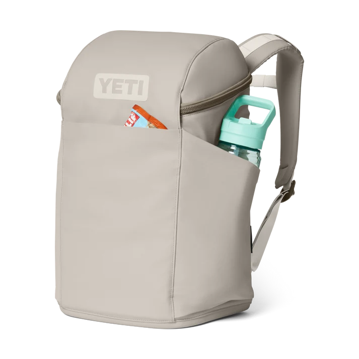 Yeti Eu Daytrip 20L backpack in Cape Taupe with front and side pockets holding a snack bar and water bottle