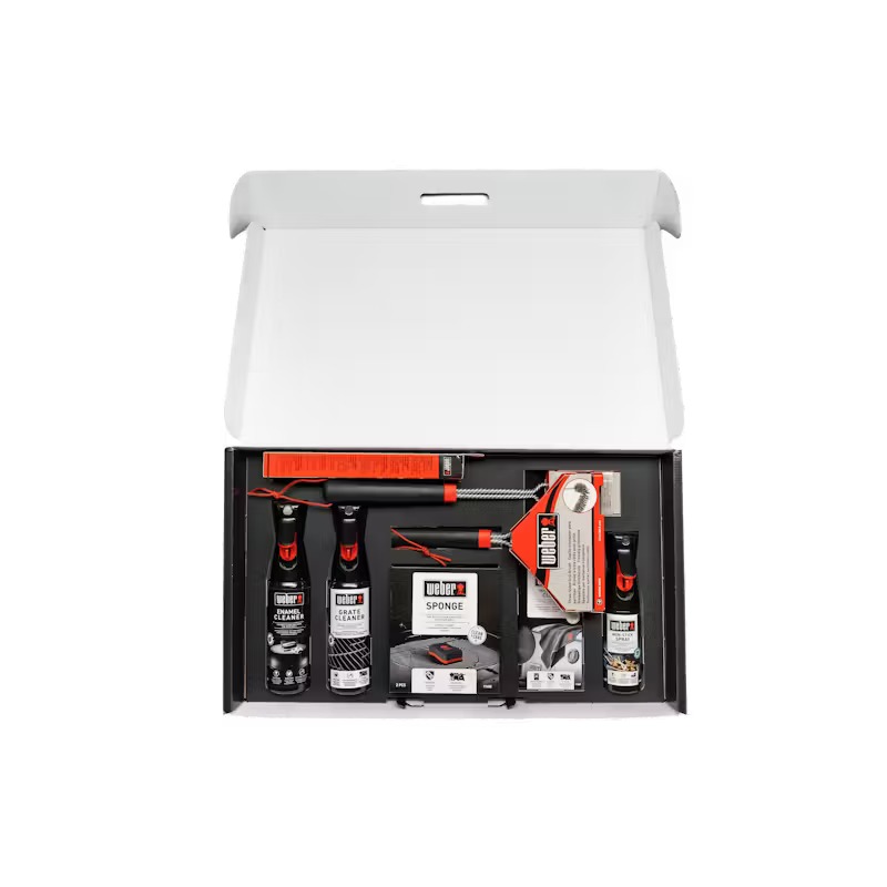 Open Weber Cleaning Kit for Enamel Gas Barbecues showing sprays, sponge, and cleaning brushes in a white box