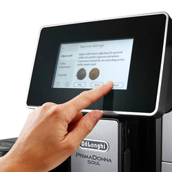 Person interacting with a De'Longhi Primadonna Soul coffee machine's touchscreen interface.