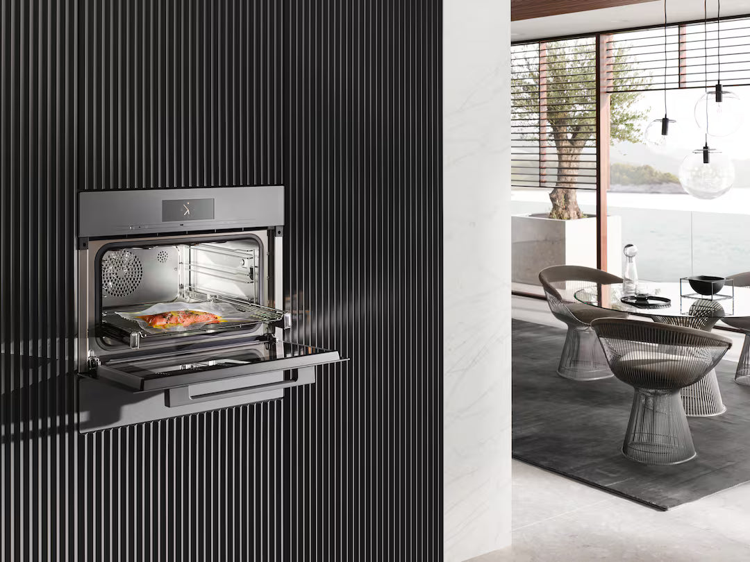 Miele EVS 7010 vacuum sealing drawer installed in black wall with food sealed inside on a tray