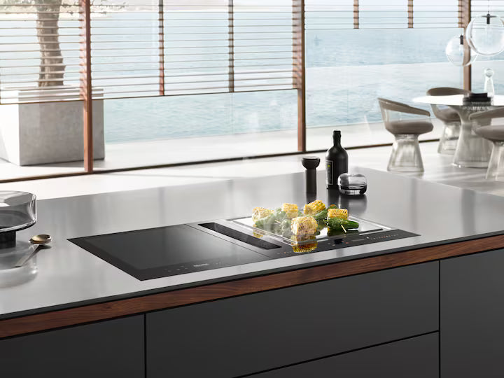 Miele SmartLine CSDA 7001 FL downdraft vent integrated into kitchen island with cooking surface and corn on the cob.