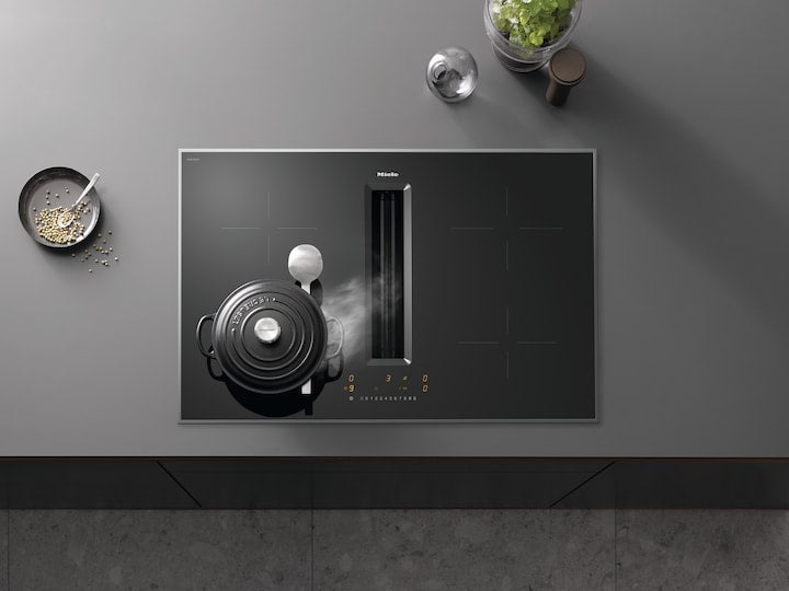 Miele KMDA7272FR-U 80cm induction hob with four cooking zones, one with a pot and steam, and integrated downdraft vent.
