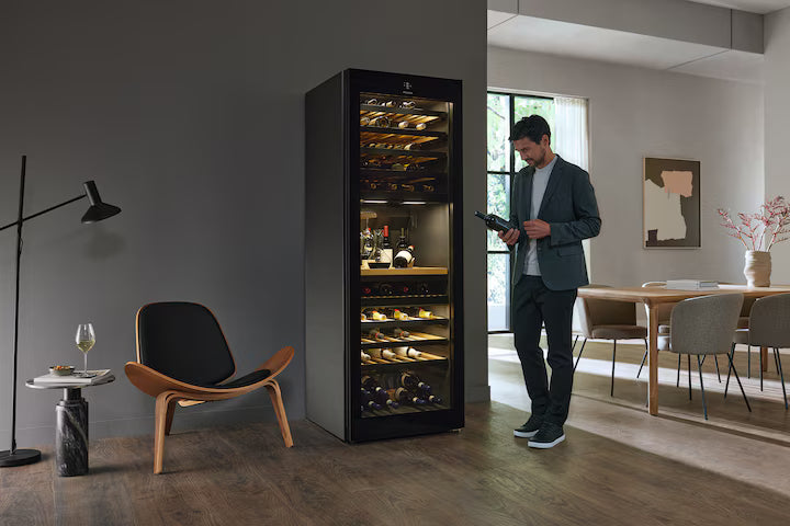 Miele KWT 4999 F built-in wine cooler with glass door, wooden shelves, and interior lighting in a modern living space.
