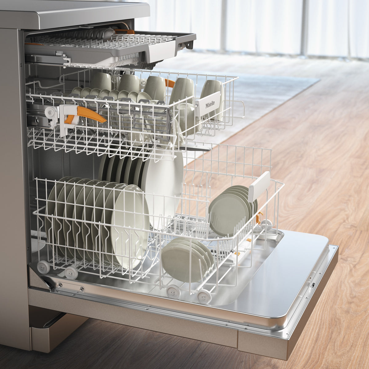 Open Miele G 5811 SC dishwasher with clean steel front, loaded with dishes and cups inside racks.