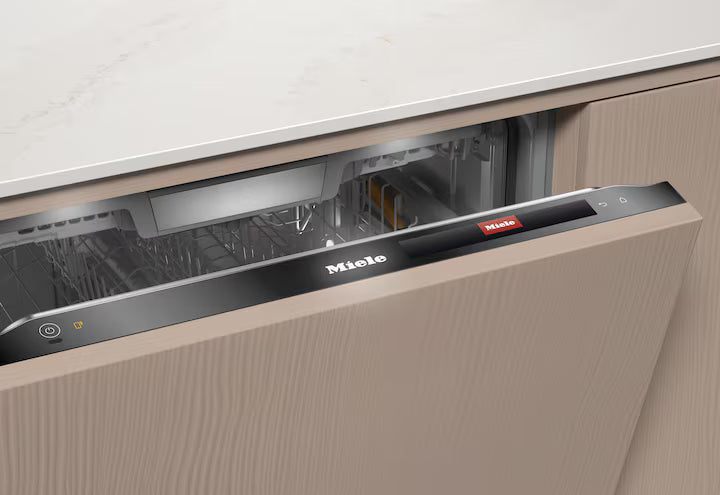 Partially open Miele G 7985 SCVi XXL dishwasher integrated into wood cabinetry with control panel visible.