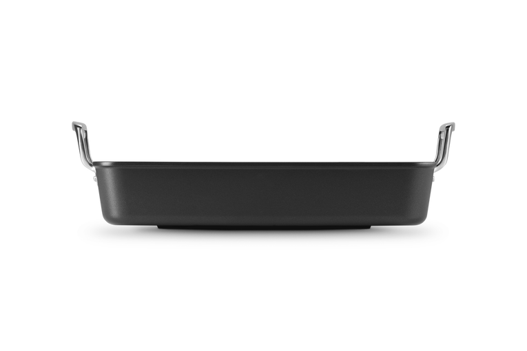 Le Creuset Toughened Non Stick Rectangular Roaster 35cm shown from side with black non-stick surface and metal handles