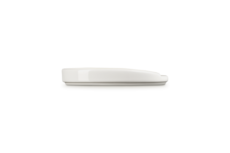 Le Creuset Oval Spoon Rest in meringue white, shown from a side profile on a white background.