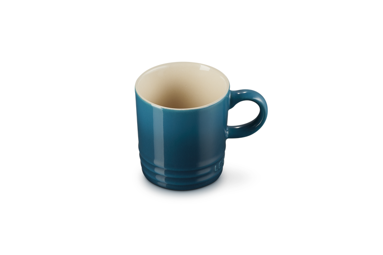 Le Creuset espresso mug in deep teal with a cream interior, shown from a slight top angle.