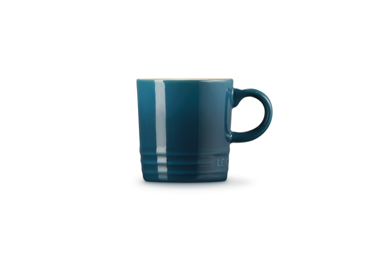 Le Creuset espresso mug in deep teal, shown from the side with handle visible on right.
