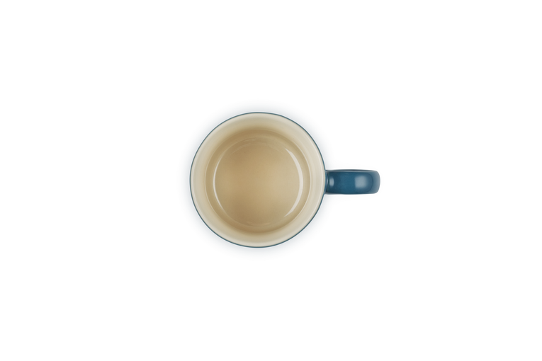 Top view of a deep teal Le Creuset espresso mug with a cream interior and handle on the right side.