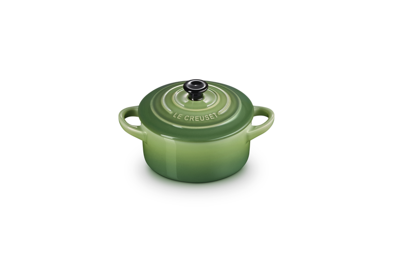 Le Creuset Petite Round Casserole in green with lid and black knob, shown from a slight top angle.