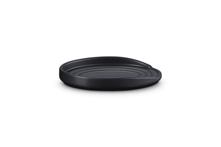 Le Creuset Stoneware Oval Spoon Rest in satin black, shown from a low front angle on a white background.