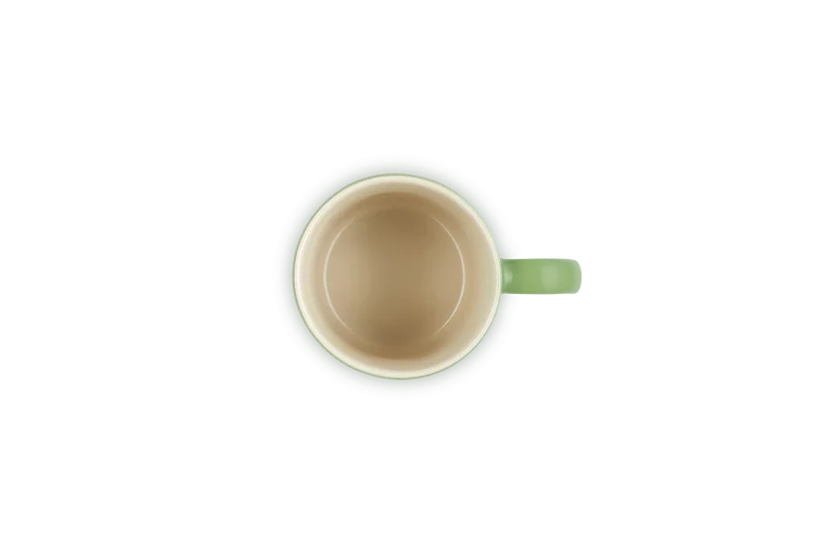 Top view of a light green Le Creuset Stoneware Espresso Mug with a 100ml capacity on a black background.