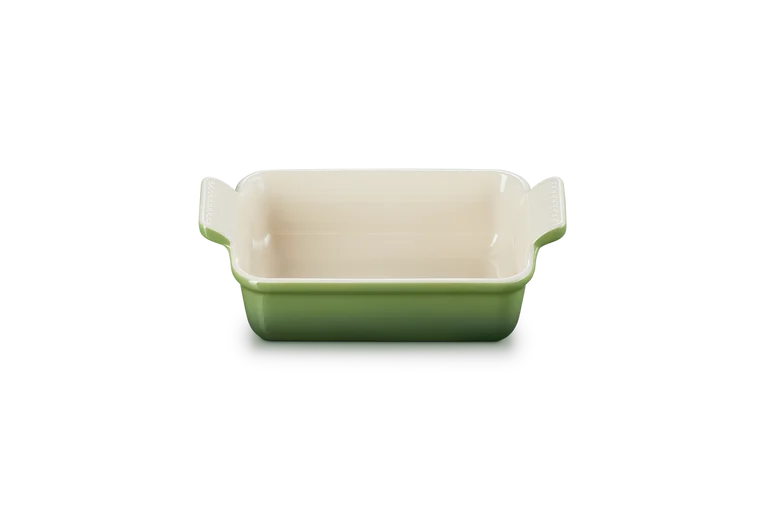 Le Creuset rectangular stoneware dish 19cm in green with cream interior and bamboo handles, front view.