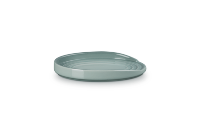 Le Creuset oval stoneware spoon rest in sea salt color, shown from a low side angle on a white background.