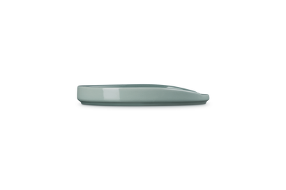 Le Creuset Stoneware Oval Spoon Rest in Sea Salt, shown from a side angle on a white background.