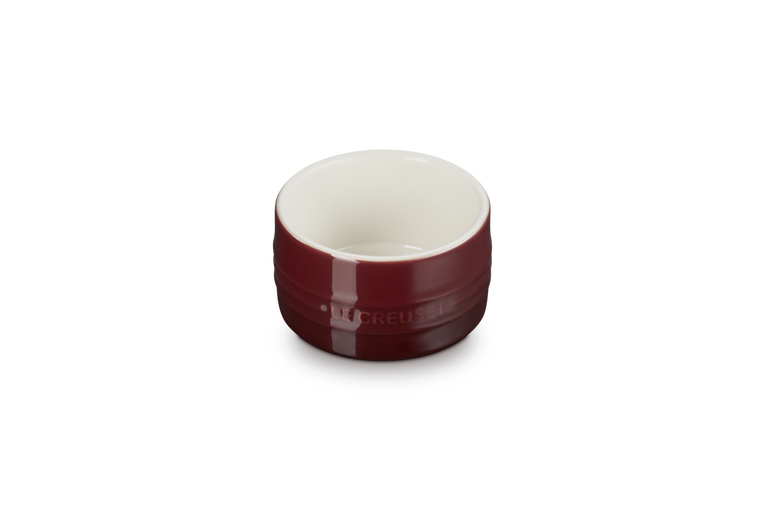 Le Creuset stoneware ramekin in garnet red with a glossy finish and white interior, front view.