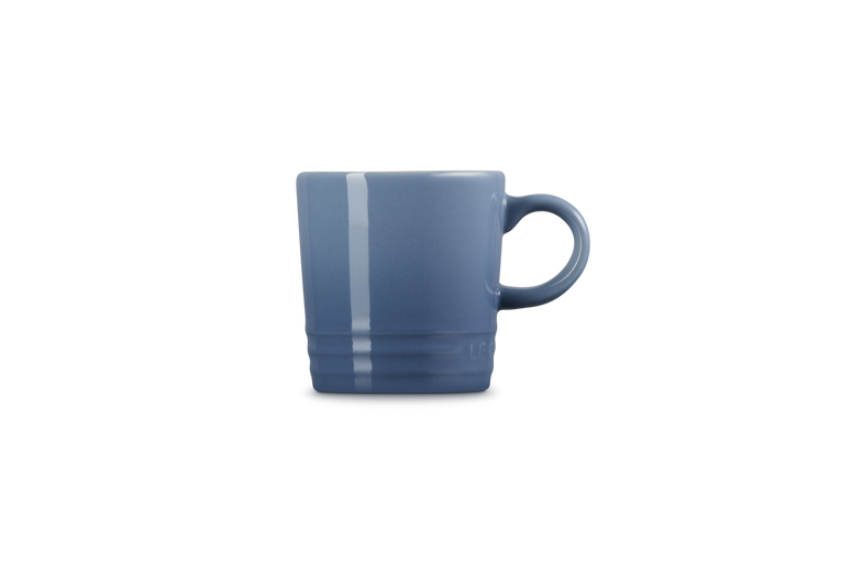 Le Creuset stoneware espresso mug in chambray blue, side view showing handle and glossy finish.