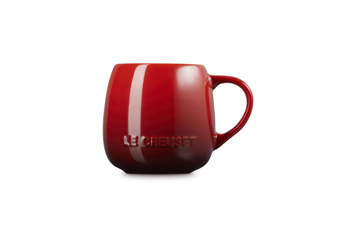 Le Creuset 320ml Coupe Mug in cerise red with embossed logo, shown from the side on a black background.